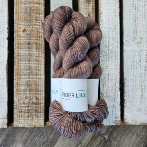 Three skeins of rich brown coloured hand dyed yarn on a wooden background