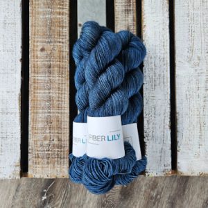 Three skeins of cobalt blue coloured hand dyed yarn on a wooden background