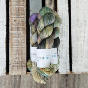 Three khaki green, blue and purple hand dyed yarn on a wooden background