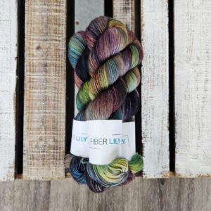 Three skeins of multi coloured hand dyed yarn next to their knit and crochet swatches