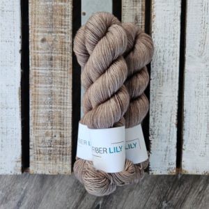 Three skeins of tonal neutral brown coloured hand dyed sock yarn in a pile on a wooden background