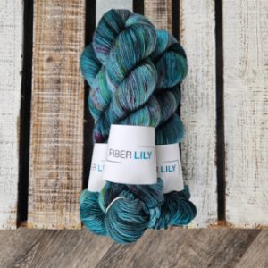 Three skeins of dark blue yarn hand dyed and speckled with purple and green