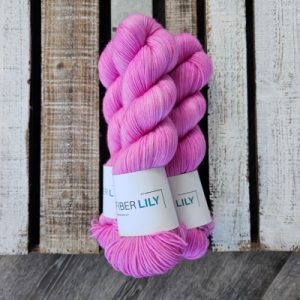 Three skeins of bubble gum pink hand dyed yarn on a wooden board