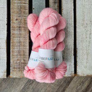 Three skeins of sweet pink hand dyed yarn on a wooden board