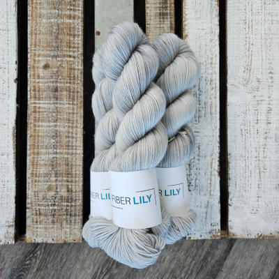 A pile of three hanks of hand dyed yarn dyed a blue grey colour