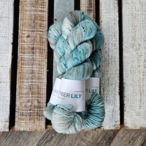 Three skeins of speckled hand dyed yarn on a wooden board