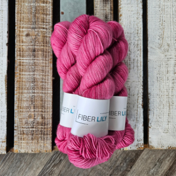 Three skeins of pink hand dyed yarn on a wooden board