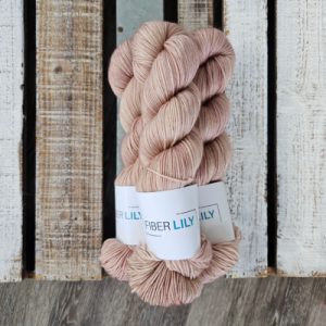 Three skeins of tonal chestnut coloured hand dyed sock yarn in a pile on a wooden background
