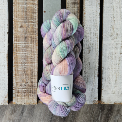 Three skeins of variegated soft lilac, aqua and pink hand dyed sock yarn on a wooden background