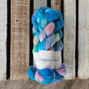 Three skeins of variegated turquoise, aqua, pink and yellow hand dyed sock yarn representing Winter colours on a wooden background