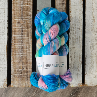 Three skeins of variegated turquoise, aqua, pink and yellow hand dyed sock yarn representing Winter colours on a wooden background