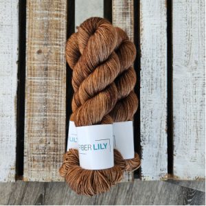 Three skeins of tonal rich warm brown hand dyed sock yarn on a wooden background