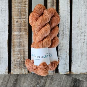 Three skeins of warm tonal caramel hand dyed sock yarn on a wooden background