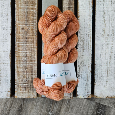 Three skeins of warm tonal caramel hand dyed sock yarn on a wooden background