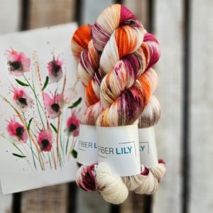 Three skeins of burgundy, orange and cream hand dyed sock yarn representing an original watercolour painting on a wooden background