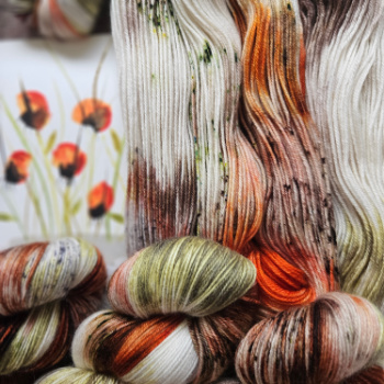 Skeins of green, brown, orange and cream hand dyed sock yarn open and twisted representing an original watercolour painting on a wooden background