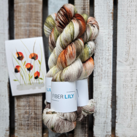 Skeins of green, brown, orange and cream hand dyed sock yarn representing an original watercolour painting on a wooden background
