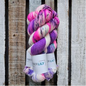 Skeins of lilac, hot pink and aqua green, hand dyed sock yarn on a wooden background