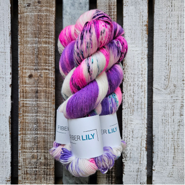 Skeins of lilac, hot pink and aqua green, hand dyed sock yarn on a wooden background
