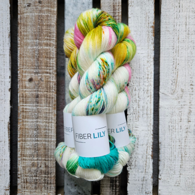 Skeins of turquoise, gold, aqua green, pink hand dyed sock yarn on a wooden background