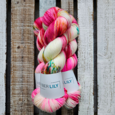Skeins of hot pink, crimson, aqua green and gold hand dyed sock yarn on a wooden background