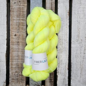 Skeins of hyper-vivid yellow hand dyed sock yarn on a wooden background