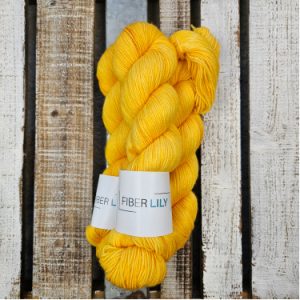 Skeins of vibrant yellow with orange undertones hand dyed sock yarn on a wooden background