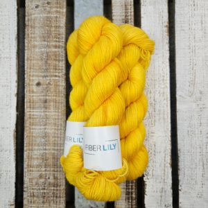 Skeins of bright yellow with gold and orange undertones hand dyed DK yarn on a wooden background
