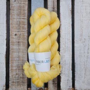 Skeins of buttery soft yellow hand dyed sock yarn on a wooden background