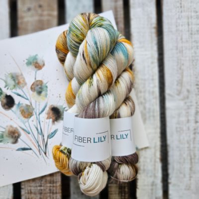 Three skeins of teal, gold, green and cream hand dyed sock yarn representing an original watercolour painting on a wooden background